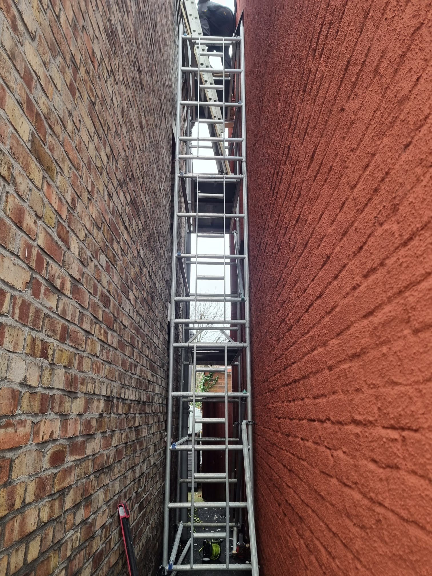 Tall scaffold tower in narrow alley between houses for roof access
